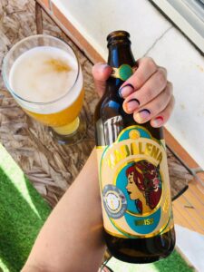 Unhas com nail art geométrica e colorida segurando a garrafa da cerveja Weiss da Cervejaria Madalena