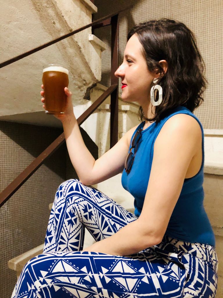 mulher sentada em escada olhando para cerveja
